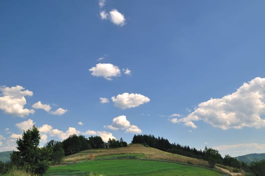 Green field in mountain and clouds on sky