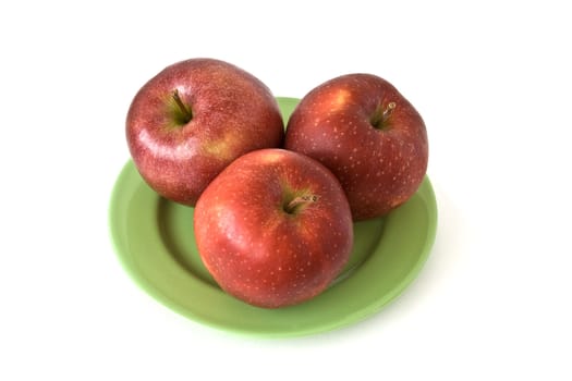 Three colored apples on wicker plate at the table