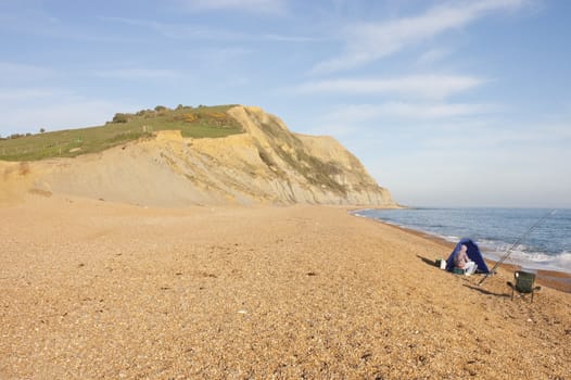 Fishermen alone on Charmouth beach on the Jurassic coast of Dorset at sunset