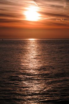 A red Dawn with aircraft vapor trails, over the Pacific Ocean in Monterey Bay 