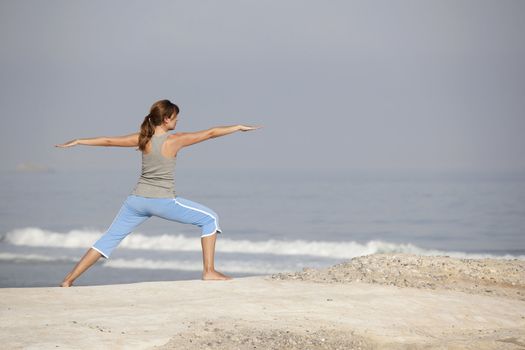 Beautiful young woman with arms open, relaxing on the beach