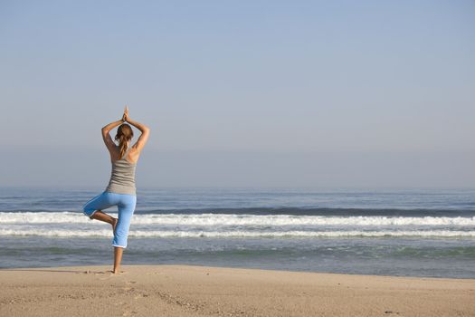 Beautiful young woman with arms open, relaxing on the beach