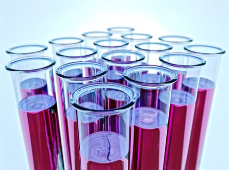 Hi-res render of sixteen test tubes containing pink fluid with  shallow depth of field and light blue background.