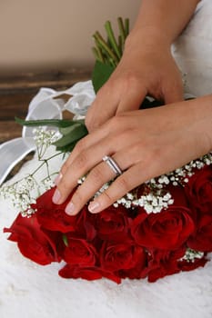 Bride resting her hand on a red rose bridal bouquet