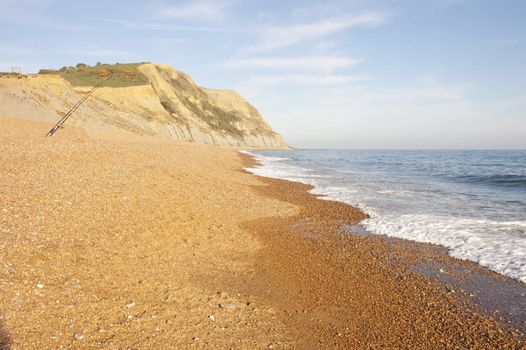 Two fishing rods on a vacant beach on the Jurassic coast of Dorset, england as the sun sets