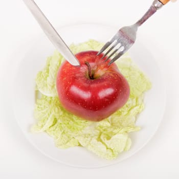 fork and knife stuck into an apple on a plate