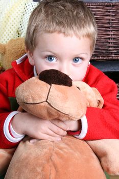 Blond boy hugging a soft toy dog