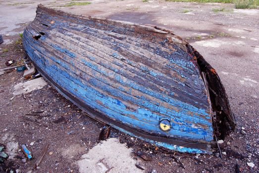 Old broken rotten boat lying on shore. Peel paint.