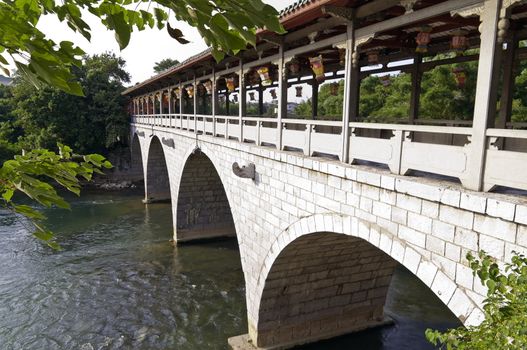 Chinese arch stone bride over a river in a city park