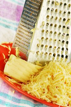 grated yellow cheese with a metal grater closeup