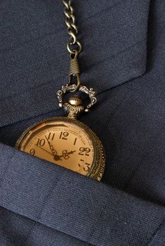 A business mans suit while checking the time on his pocket watch.