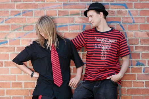 Young punk couple against brick wall