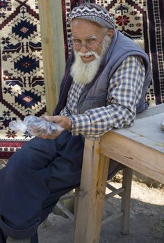 A very nice old man selling organic plums from his garden and carpets his granddaughter makes 