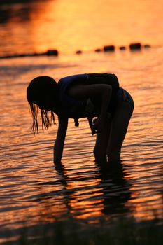 Little girl searching for shells at sunset