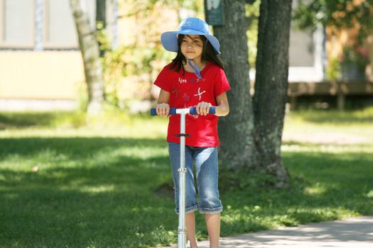 Girl riding a scooter on sidewalk