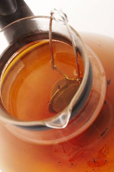 macro pic of glassy teapot with strainer over white