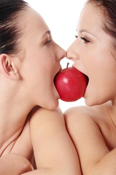 Two young woman biting an apple, isolated on white