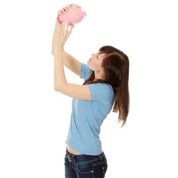Savings concept - a woman with a piggy bank trying to get out some money - isolated over white 