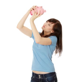 Savings concept - a woman with a piggy bank trying to get out some money - isolated over white