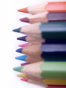 Assortment of coloured pencils with shadow on white background.
