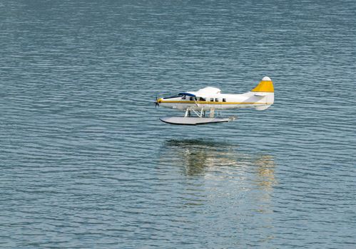 single engined seaplane coming into land with a reflection just prior to touch down