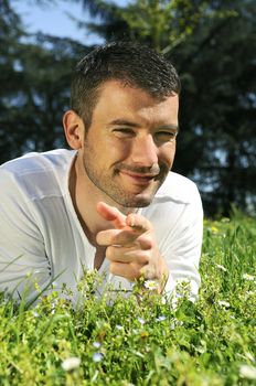 An attractive and cheerful man lying in the park