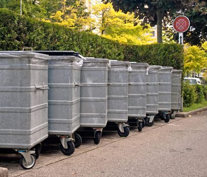 Metal garbage bins on a street lined an a row