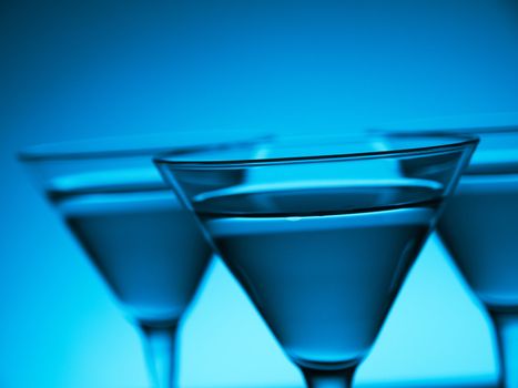 Three glasses of martini on blue background