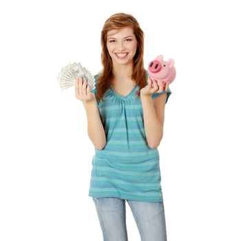 Happy teen holding a piggy bank and dollars, isolated on white background