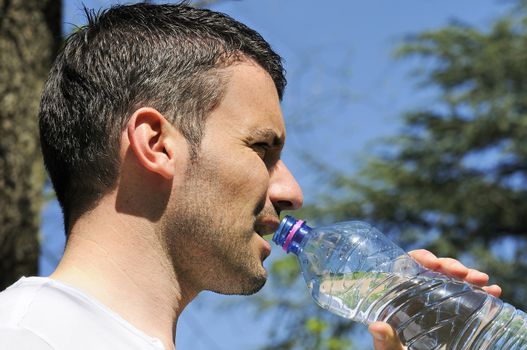 Man is drinking water against a natural background