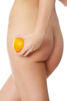 Naked woman's buttocks with orange. Cellulite concept