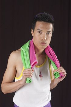 closeup of a young asian man on a black background with towel around neck