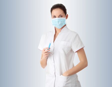 Young nurse in mask with syringe,  over gray background