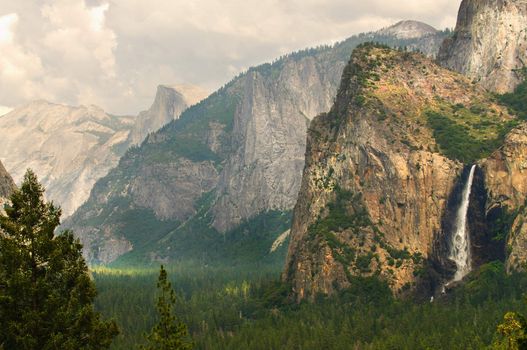 view of bridleveil falls and half dome with clouds creating a patchwork of light dancing across  Yosemite national Park, California