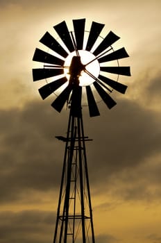 Silhouette of an old fashioned windmill against cloudy sunset sky