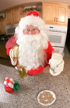 Santa in kitchen whipping up a batch of cookies, then eating some of them with a glass of milk