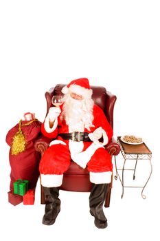 Santa sitting in an armchair drinking a glass of scoth or brandy with some cookies after a very bust night