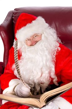 Humorus closeup of Santa Claus (that jolly old elf that  lives at the North Pole) reading and writing in the book of good children