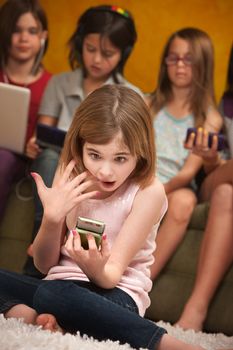 Surprised little Caucasian girl with a handheld device 