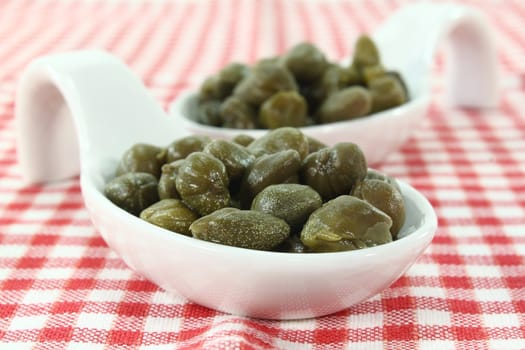 pickled caper berries on a white spoon