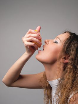 Young woman squeezing an orange to get juice