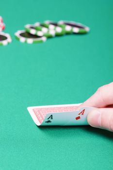 poker player with two aces and chips on a green table
