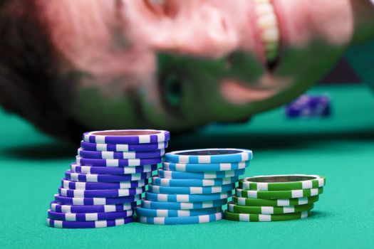 Chips on the background of a happy male face on a green table casino
