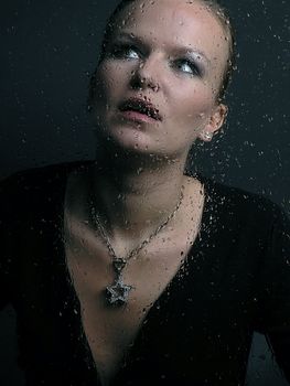 Womans face behind glass with rain drops