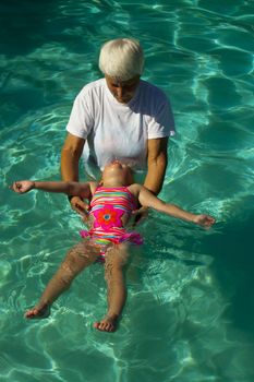 Grandmother helping 3 year old learn how to float