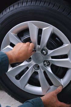 Mechanic working on car using various tools to change tires on a vehicle.