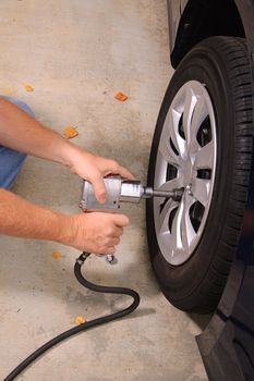 Mechanic working on car using various tools to change tires on a vehicle.