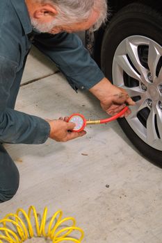 Mechanic working on car using various tools to change tires on a vehicle.