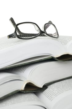 Glasses on pile of books on white background