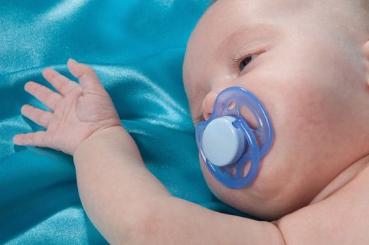 a sweet baby sleeping on a blue satin sheet